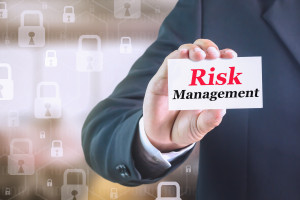 A businessman holding up a card with the word risk management.