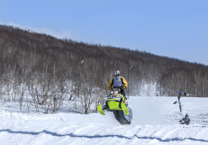 A person riding a snowmobile down a snowy hill.