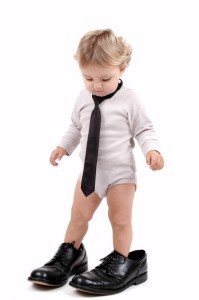 A baby wearing a tie and black shoes on a white background.