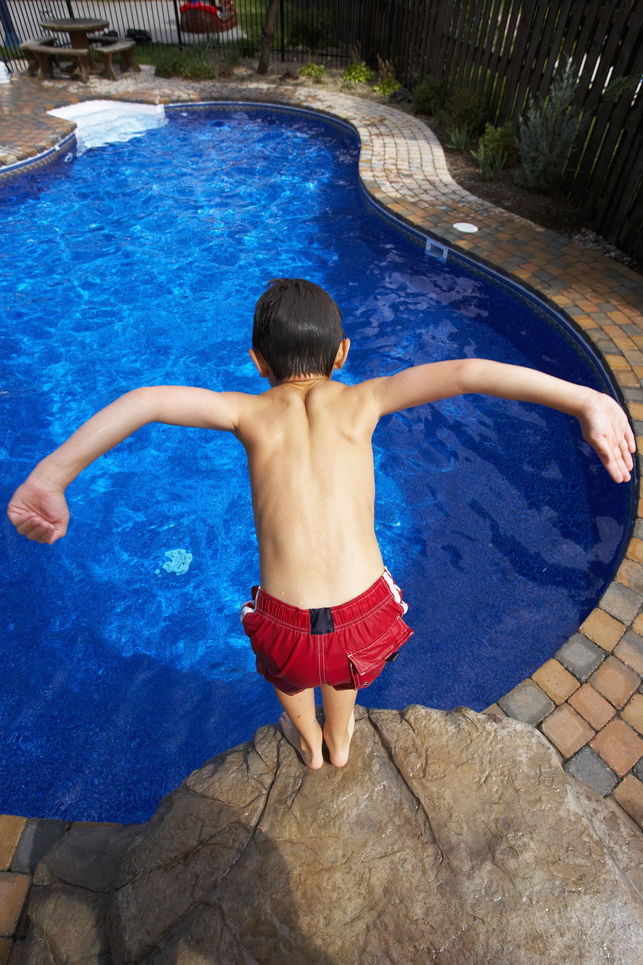 A boy jumping into a swimming pool.