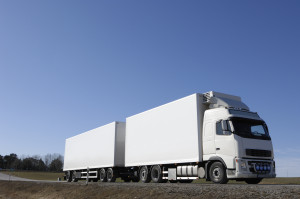 A white semi truck driving down a country road.