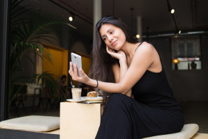 A woman is sitting on a bench and using her cell phone.