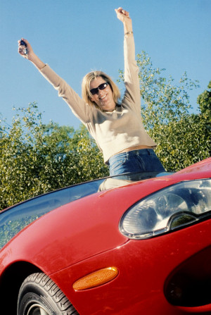 A woman on top of a red sports car.