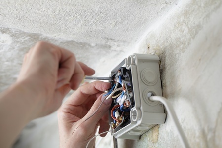 A person is working on an electrical outlet in a room.