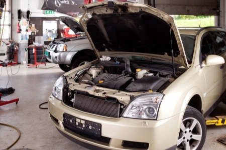 A car with its hood open in a repair shop.