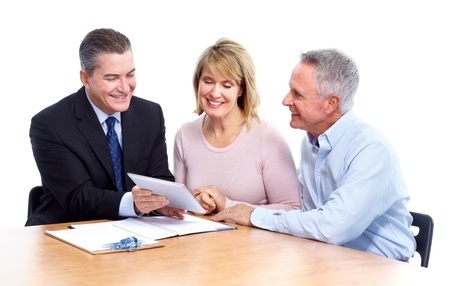 Three people sitting at a table looking at a tablet.