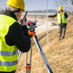 Two construction workers using a surveying equipment.