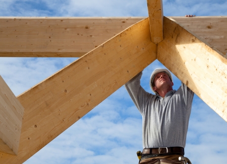 A construction worker is working on a wooden frame.