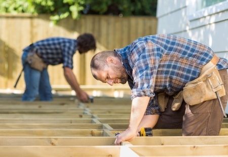 Two men working on a wooden deck.