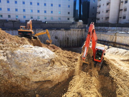 A red excavator is digging a hole in the ground.