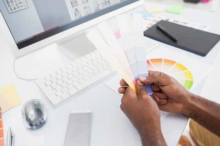 A man is using color swatches on a desk.