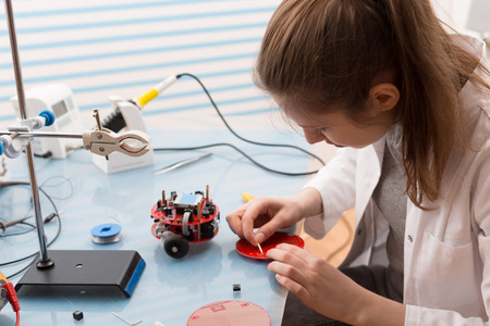 A young woman is working on a small electronic device.