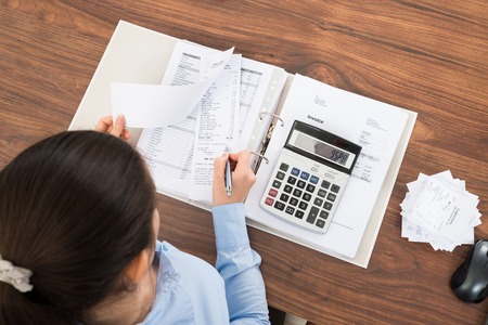 A woman is working on her taxes with a calculator and papers.