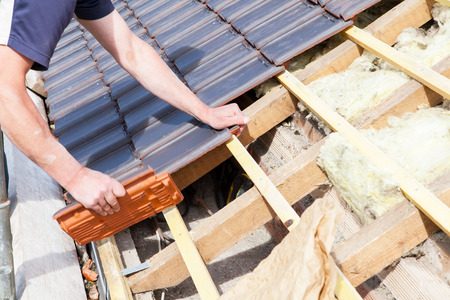 A man installing a tile roof on a house.