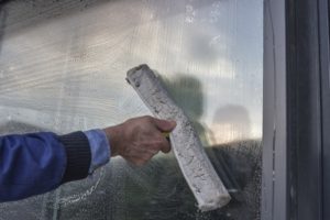 A man cleaning a window with a brush.