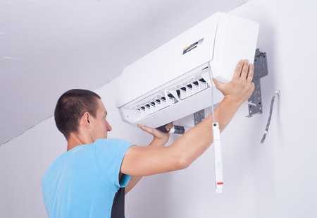 A man installing an air conditioner in a room.