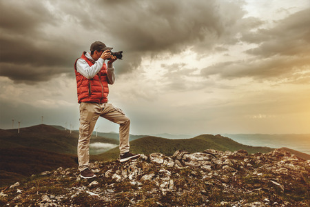 A man with a camera standing on top of a mountain.