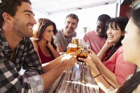 A group of friends toasting at a bar.