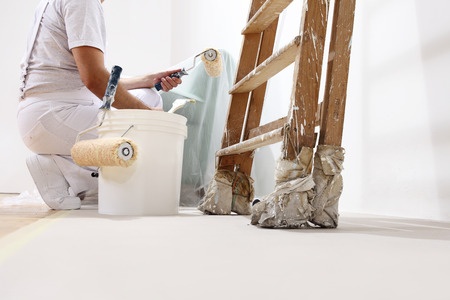 A woman painting a room with a paint roller.