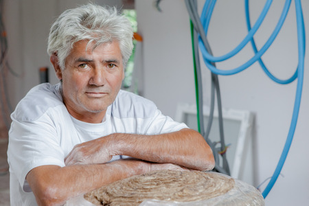 A man sitting on a piece of wood in a construction site.