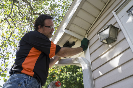 A man fixing the gutters of a house.