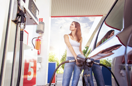 A woman filling up her car at a gas station.