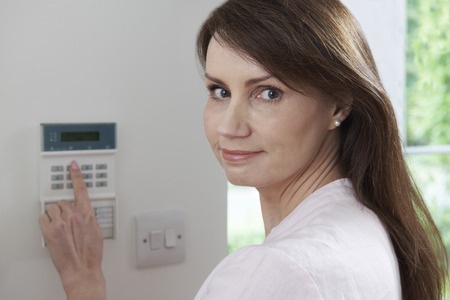 A woman is pointing at a home security system.