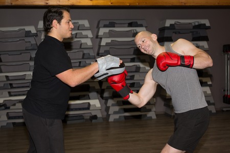 Two men in boxing gloves in a gym.