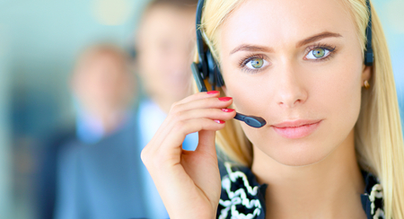 A blond woman wearing a headset and talking to a group of people.