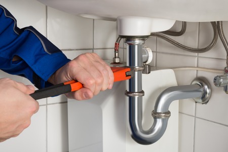 A plumber fixing a sink in a bathroom.