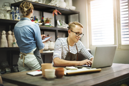 A man and woman working on a laptop in a shop.