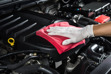 A person is cleaning the engine of a car.