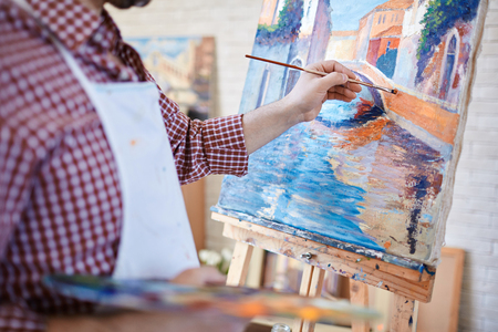 A man is painting on an easel in an art studio.