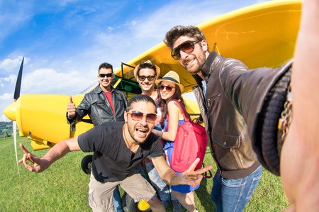 A group of friends taking a selfie in front of an airplane.