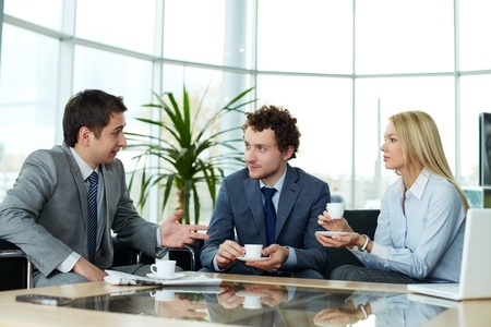 A group of business people sitting around a table in an office.