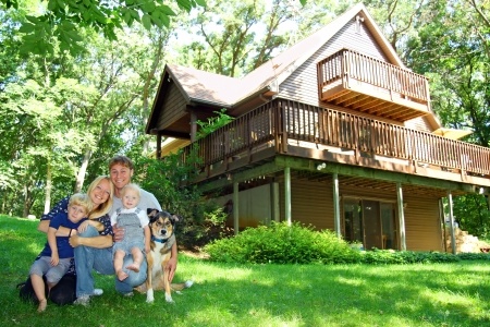 A family posing in front of a house with a dog.