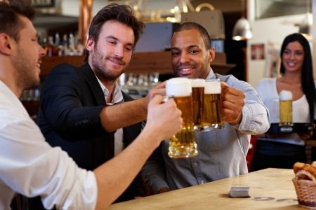 A group of friends toasting beer in a bar.