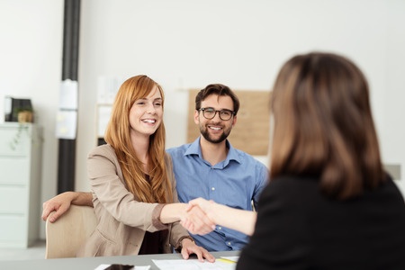 Smiling businessman and woman shaking hands in office stock photo.