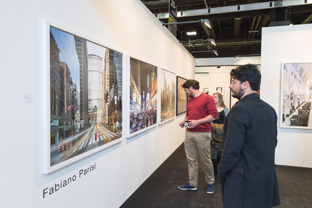 A group of people looking at pictures on a wall.