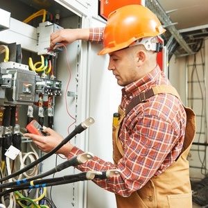 A man is working on an electrical panel.