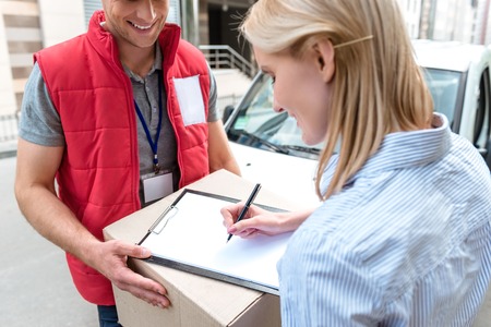 A woman is signing a document with a delivery man.