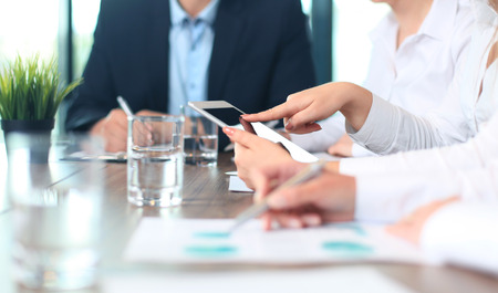 A group of business people using their cell phones at a meeting.