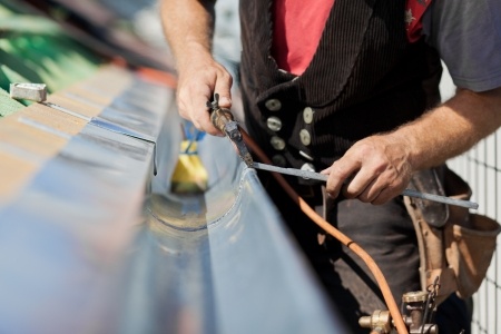 A man is working on a metal roof.