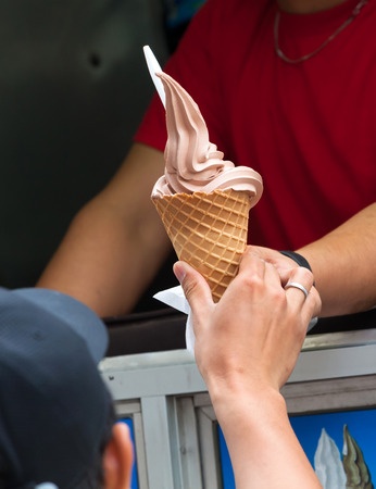 An ice cream cone being handed to a person.