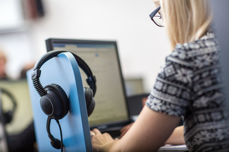 A woman wearing a headset in front of a computer.