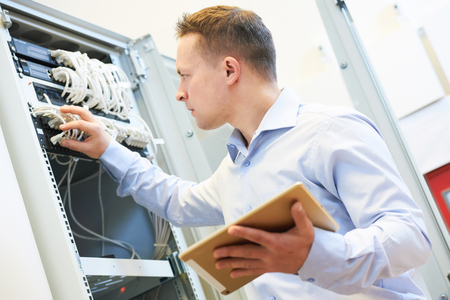 A man is working on a server in a server room.