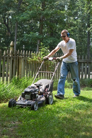 A man is mowing his lawn with a lawn mower.