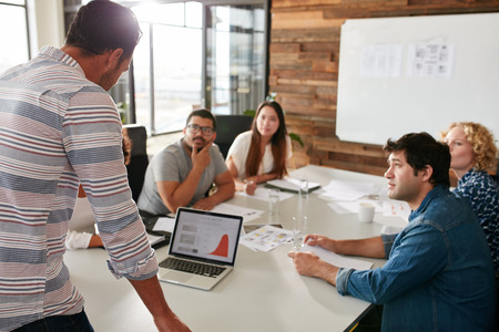 A group of people sitting around a table in a meeting room.