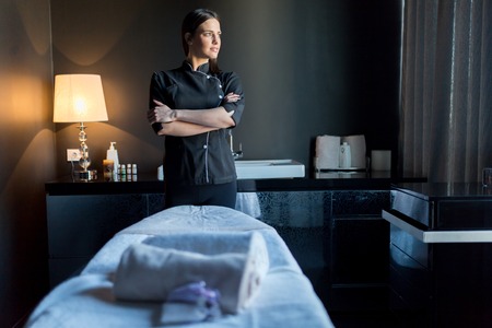 A woman is standing in front of a massage table.