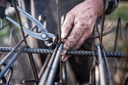 A man is working with pliers on a piece of metal.